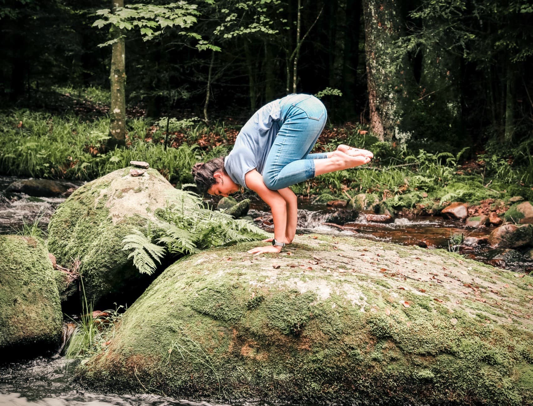 Kräftigende Yoga-Pose auf einem Felsen im Wald